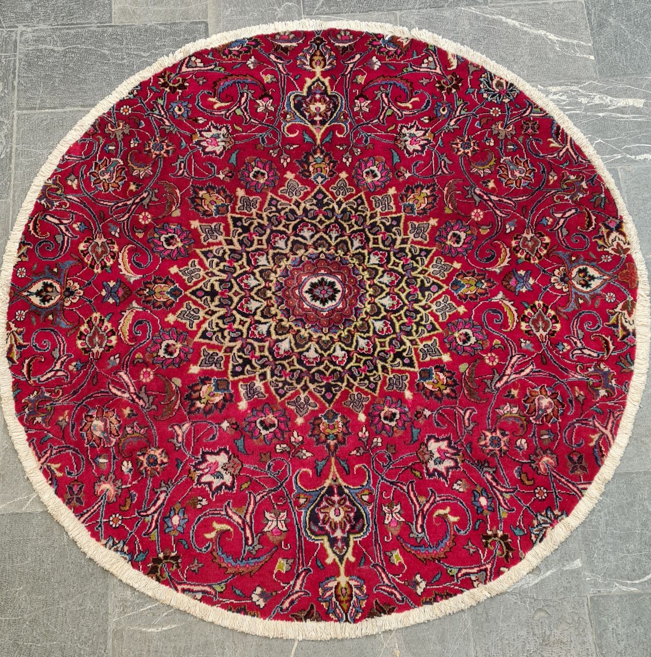فرش دستباف مشهد دایره شده طرح لچک و ترنج سایز فرش گرد ۲×۲ رنگ زمینه لاكي رنگ حاشیه سرمه اي کد ۴۲۸۵۹